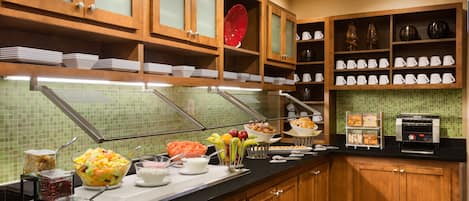 A buffet setup with various food items and utensils.