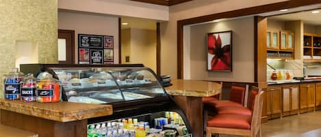 Un bar à petit-déjeuner doté d’une vitrine réfrigérée, d’un espace salon et d’un coin café.