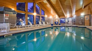 Une piscine intérieure dotée de chaises longues et d’un plafond en bois.