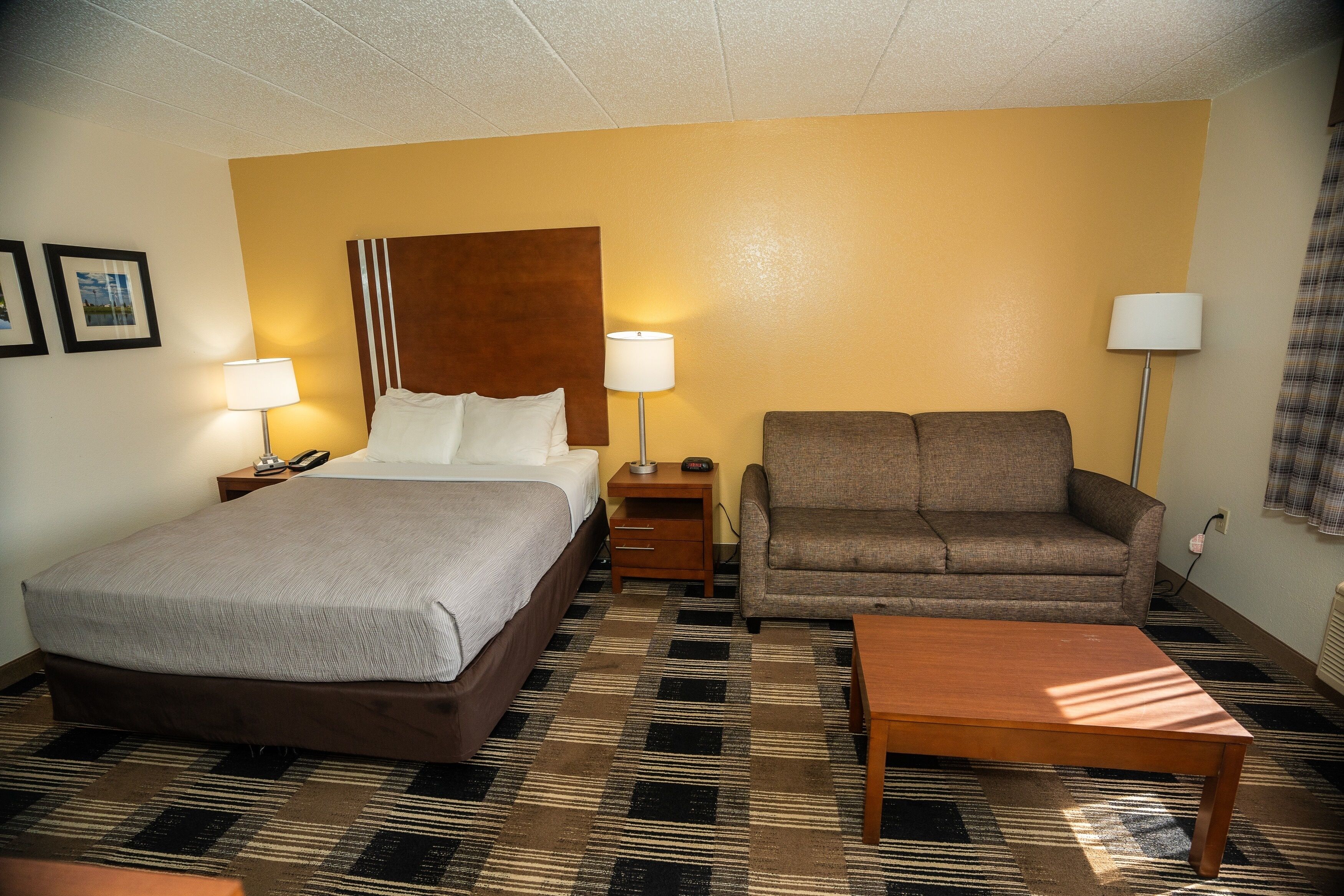 A hotel room with a bed, a sofa, a coffee table, and two bedside lamps.