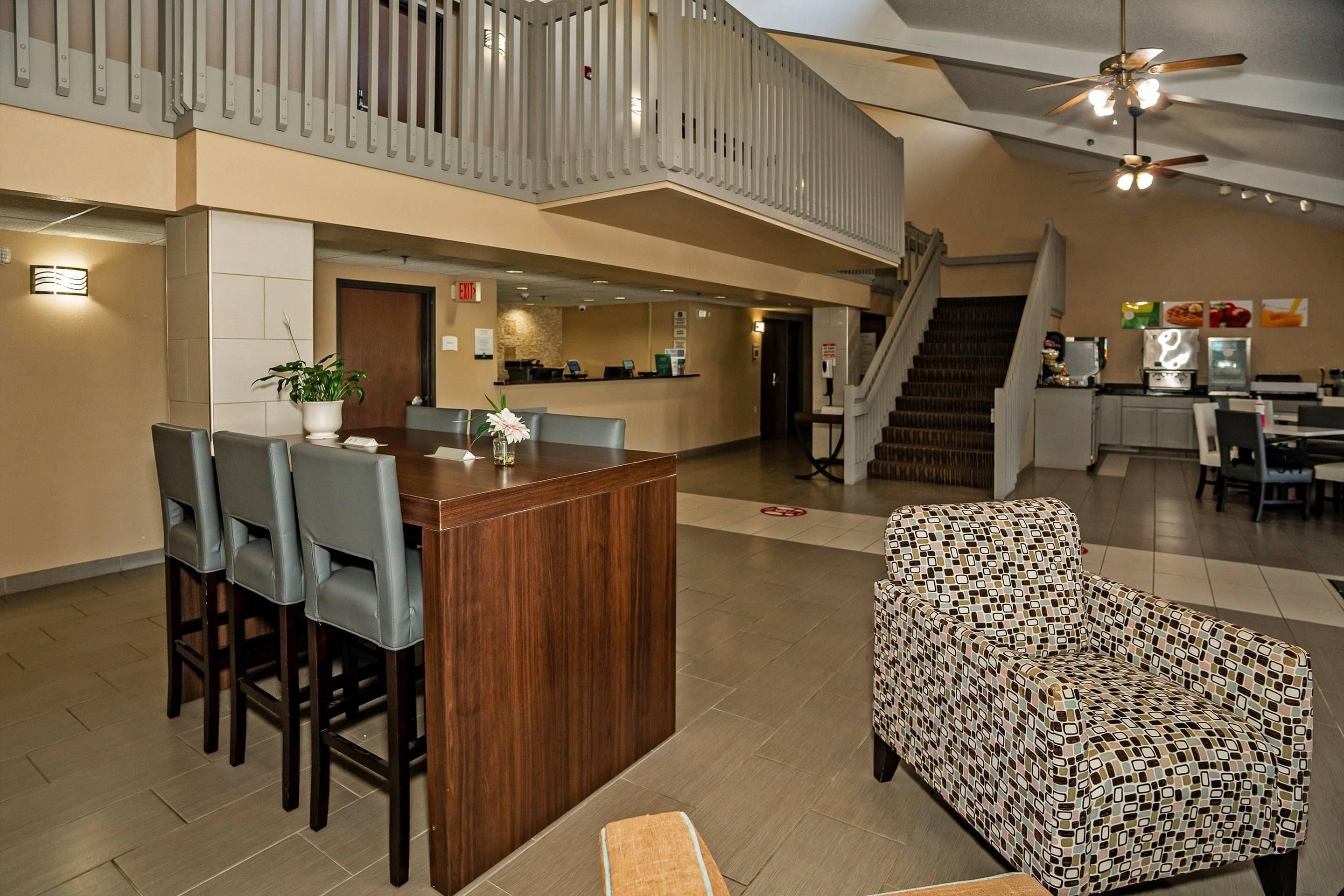 A spacious lobby with a reception desk, seating area, staircase, and a patterned armchair.