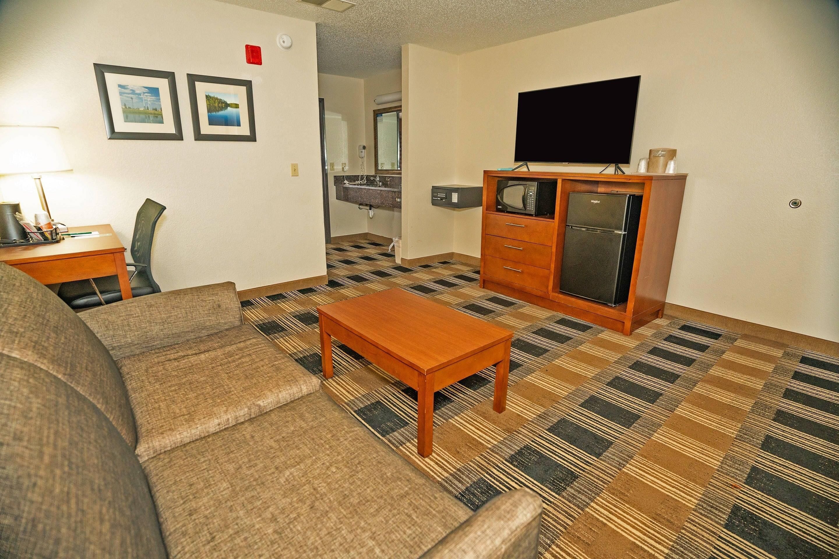 A living room with a sofa, a wooden coffee table, a television, and a microwave.
