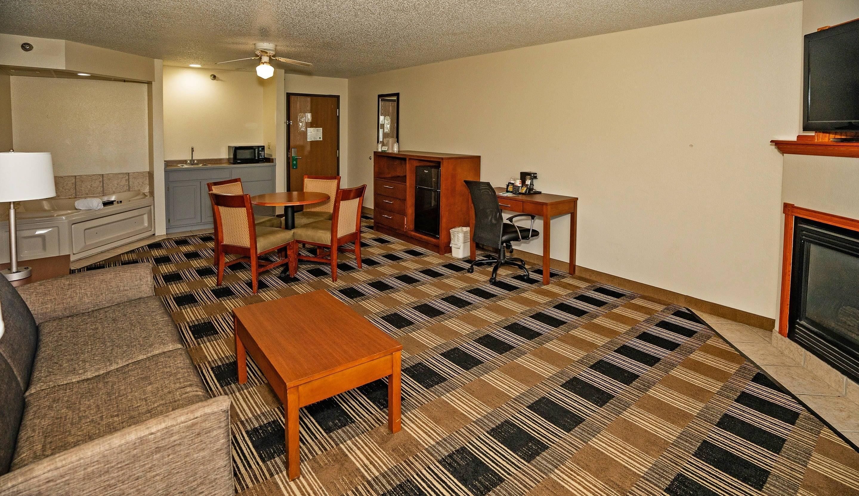 Una sala de estar compacta con un sofá, una mesa de madera, una mesa de comedor, una kitchenette, un televisor y una chimenea.
