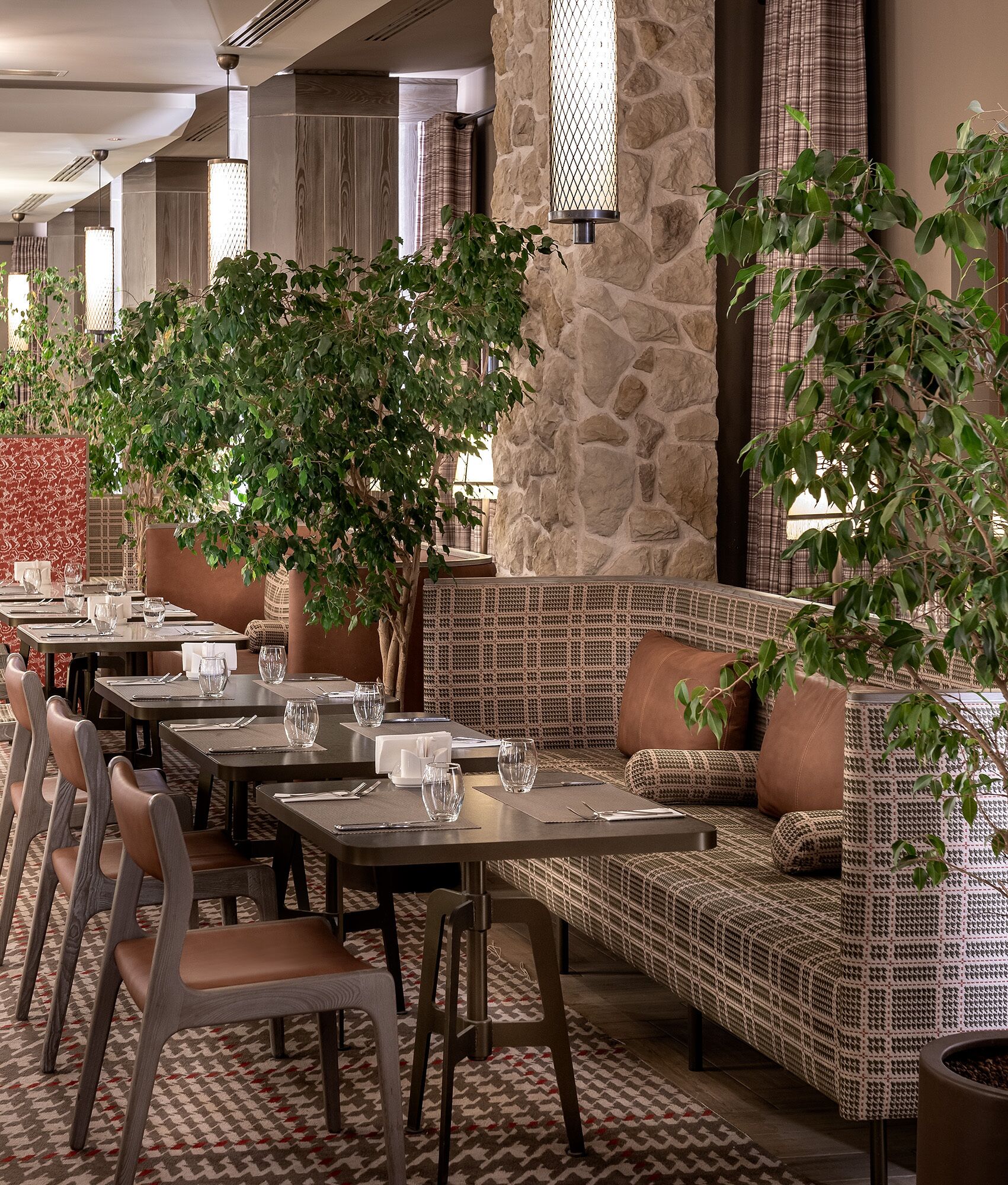 A restaurant with tables and chairs, stone walls, and potted plants.