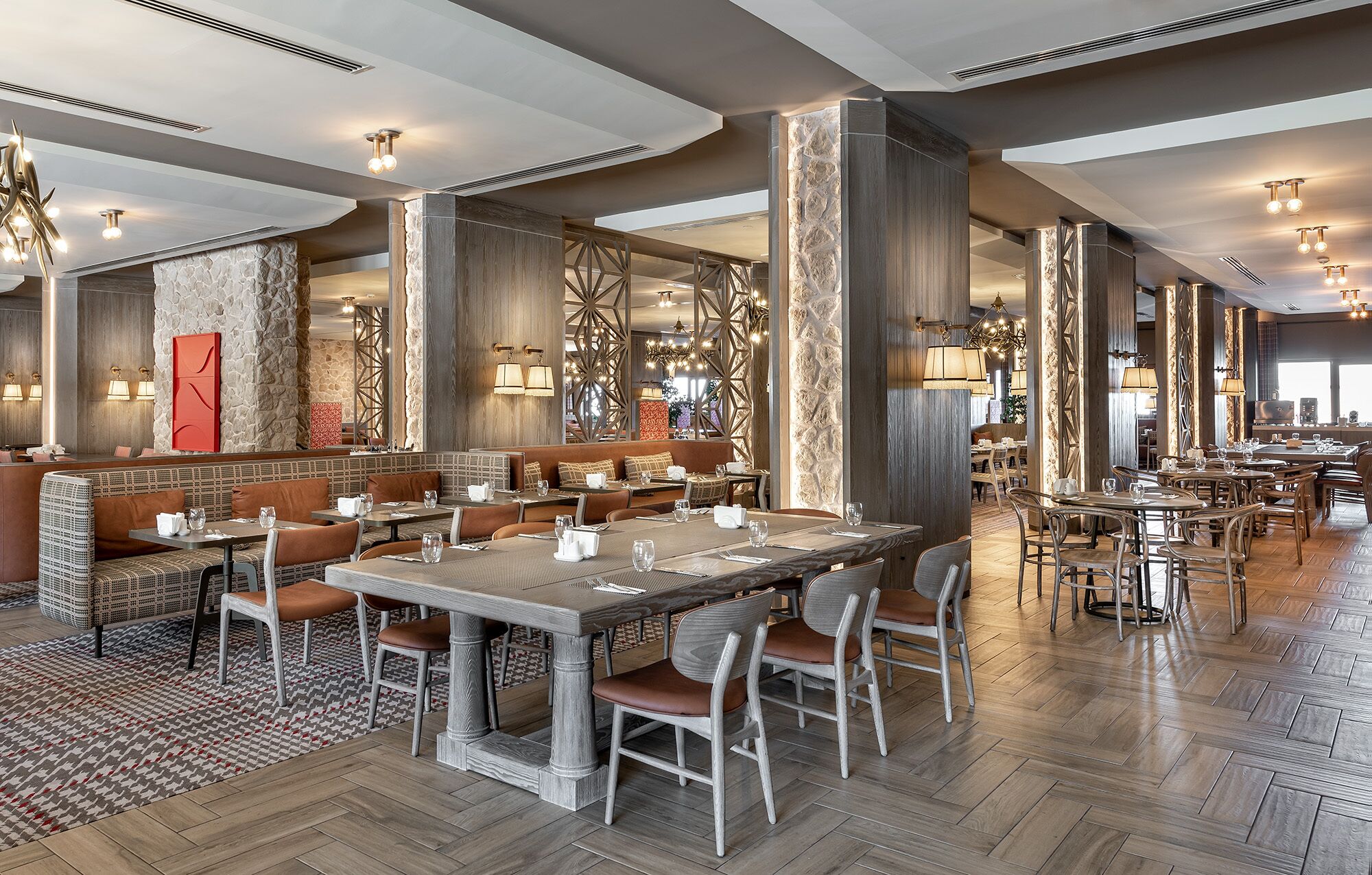 A spacious restaurant with high ceilings, modern chandeliers, and a mix of seating options including booths and tables.