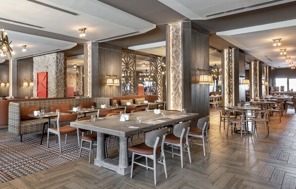 A spacious restaurant with high ceilings, modern chandeliers, and a mix of seating options including booths and tables.