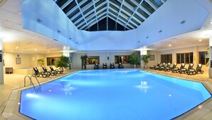 An indoor swimming pool with a skylight ceiling, lounge chairs, and a reception area. - Polat Palandoken (Erzurum)
