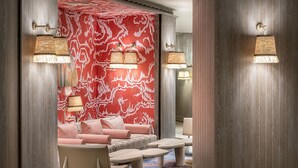 A room with a red patterned wall, wooden paneling, and two wall-mounted lamps. - Polat Palandoken (Erzurum)