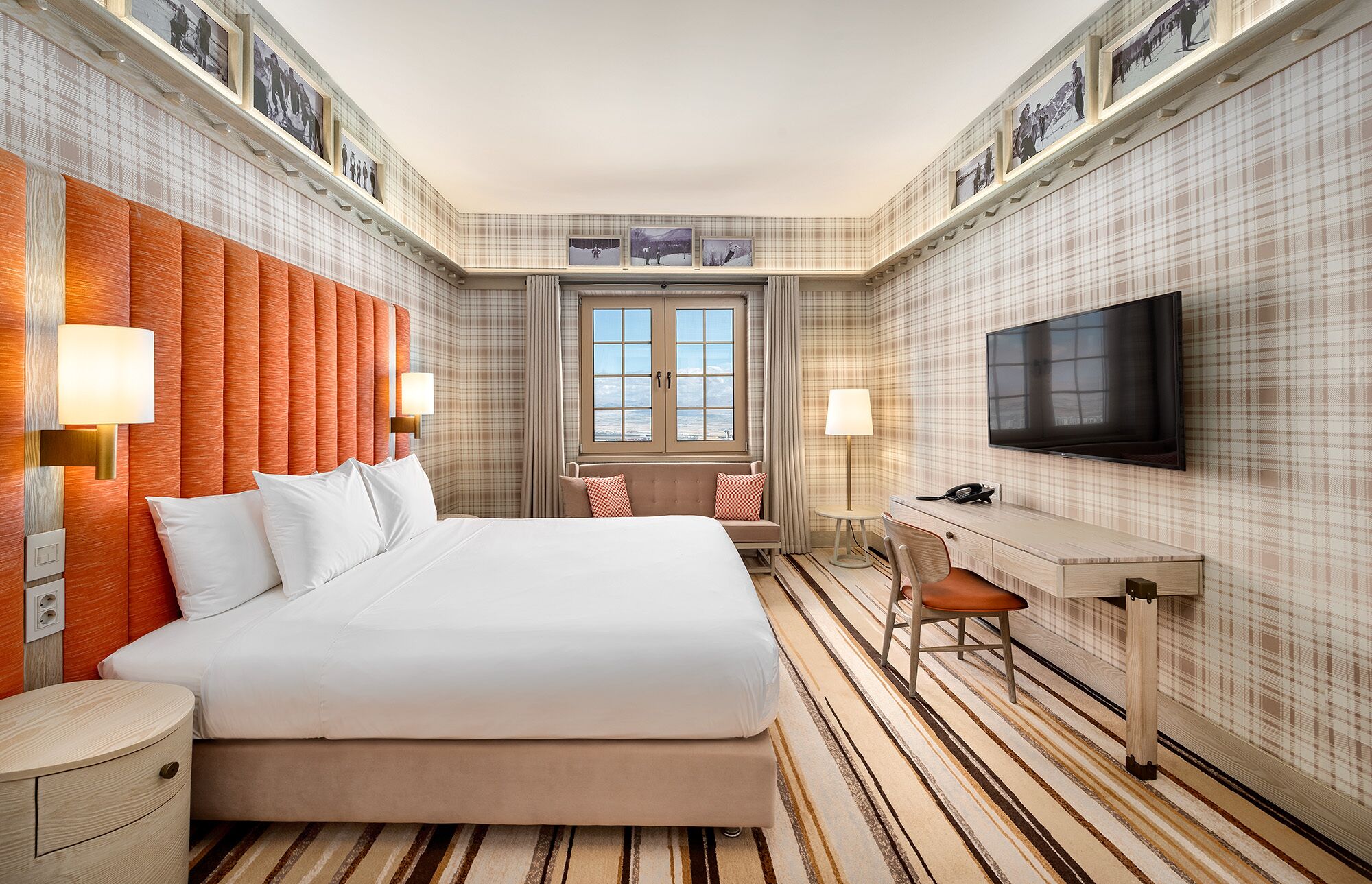 Une chambre d’hôtel avec un grand lit, un bureau, une télévision et une fenêtre donnant sur un beau paysage.