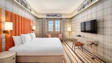 Une chambre d’hôtel avec un grand lit, un bureau, une télévision et une fenêtre donnant sur un beau paysage.