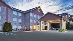 Um hotel Comfort Inn com fachada de tijolos, entrada coberta e estacionamento.