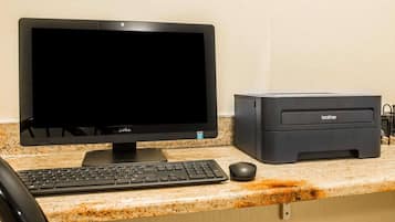 Um computador desktop com monitor, teclado e rato sobre uma bancada de granito.