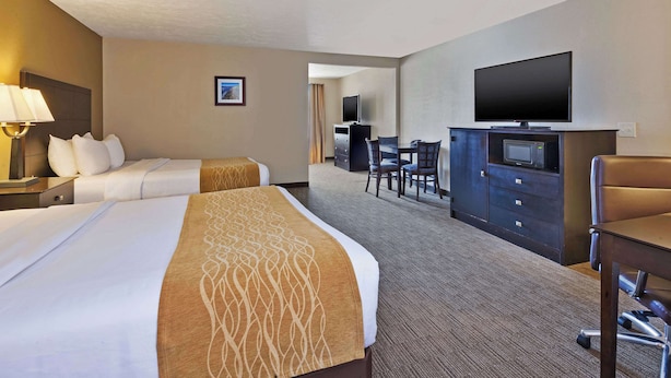 Quarto de hotel com duas camas, uma escrivaninha, televisão e área de estar.