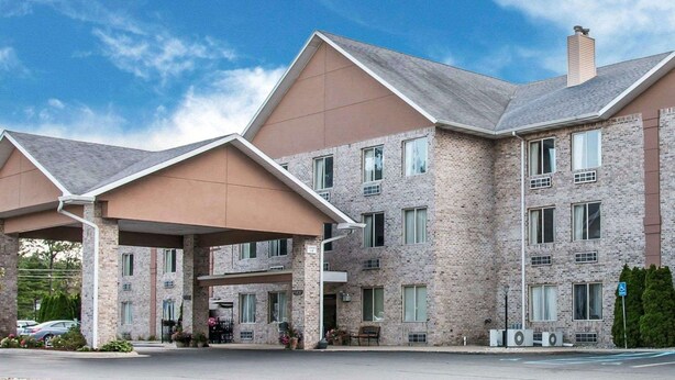 A multi-story hotel with a brick facade, multiple windows, and covered parking areas.
