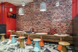 Una habitación con pared de ladrillo, varias mesas con taburetes y lámparas colgantes.