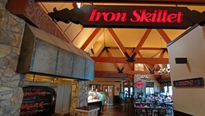 Restaurante Iron Skillet con pared de piedra y zona de parrilla.