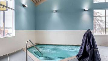 A swimming pool with a metal ladder, a covered bench, and two wall-mounted lights.