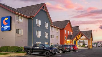 Un hotel Comfort Inn con un estacionamiento, varios vehículos y cielo despejado.