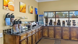 Un espace pour le petit-déjeuner à l’hôtel, équipé d’un coin café, d’un four à micro-ondes et offrant une vue sur la ville grâce à de grandes fenêtres.