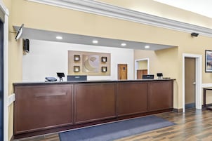 A reception desk with a modern design, a large wall-mounted artwork, and a wooden door in the background.