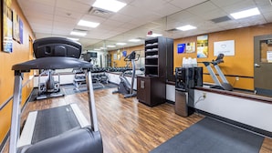 Une salle de sport équipée de tapis de course, de vélos d’exercice et de poids.