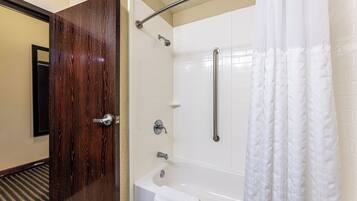 Un baño con una bañera blanca, una ducha con puerta de cristal y una puerta de madera.