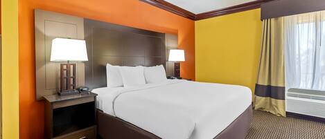 Habitación de hotel con una cama grande, dos mesitas de noche con lámparas, un televisor de pantalla plana y una ventana con cortinas.