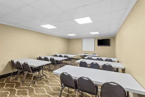 A conference room with multiple tables and chairs, a projector screen, and a carpeted floor. - Comfort Suites Lake Jackson Clute (Lake Jackson)