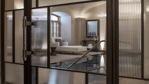 A modern hotel room with a glass partition, a white sofa, a small table, and a mirror. - Four Seasons Hotel Prague (Prague)