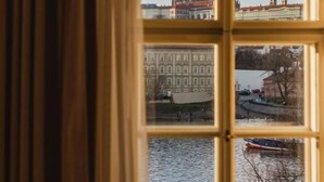 A window with a view of a cityscape, including a prominent building with spires and a river. - Four Seasons Hotel Prague (Prague)