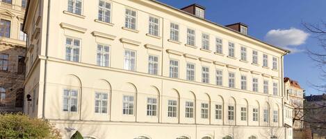 A large, cream-colored building with multiple windows and a symmetrical facade.