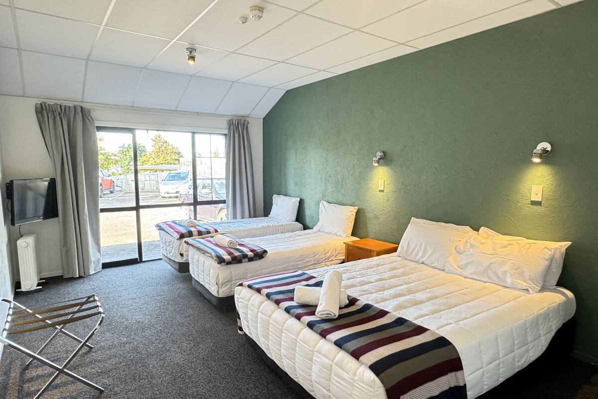 A hotel room with two beds, a TV, and a view of the parking lot.