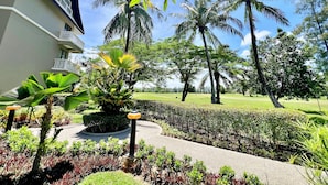 A landscaped garden with palm trees, a pathway, and a building with a balcony. - Allamanda Laguna Phuket by RESAVA (Choeng Thale)