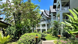 A hotel with multiple balconies, lush greenery, and a clear sky. - Allamanda Laguna Phuket by RESAVA (Choeng Thale)