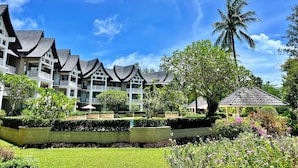 A hotel with multiple buildings featuring traditional architectural style, surrounded by well-maintained gardens and palm trees. - Allamanda Laguna Phuket by RESAVA (Choeng Thale)