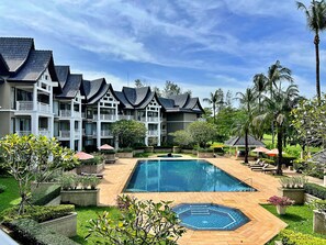 Un hotel con piscina, varios balcones y abundante vegetación.