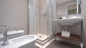 A modern bathroom with a glass-enclosed shower, a white sink, and a mirror above the sink.