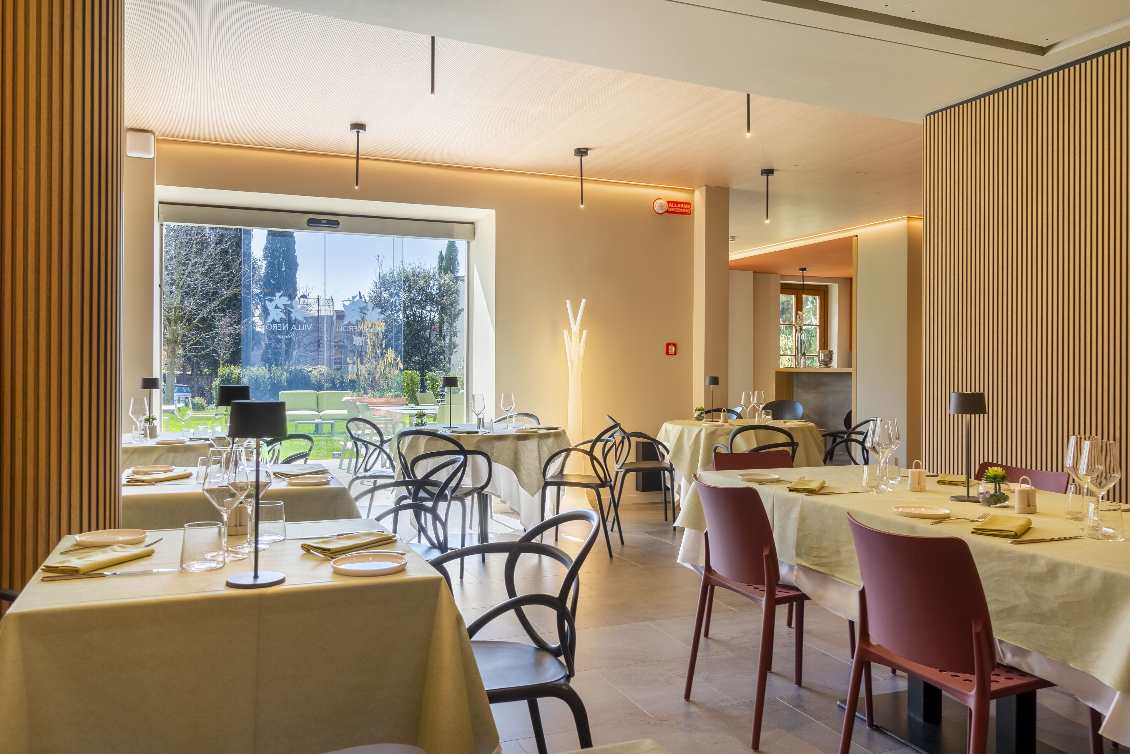 A restaurant with tables set for dining, a view of greenery outside, and a modern interior design.