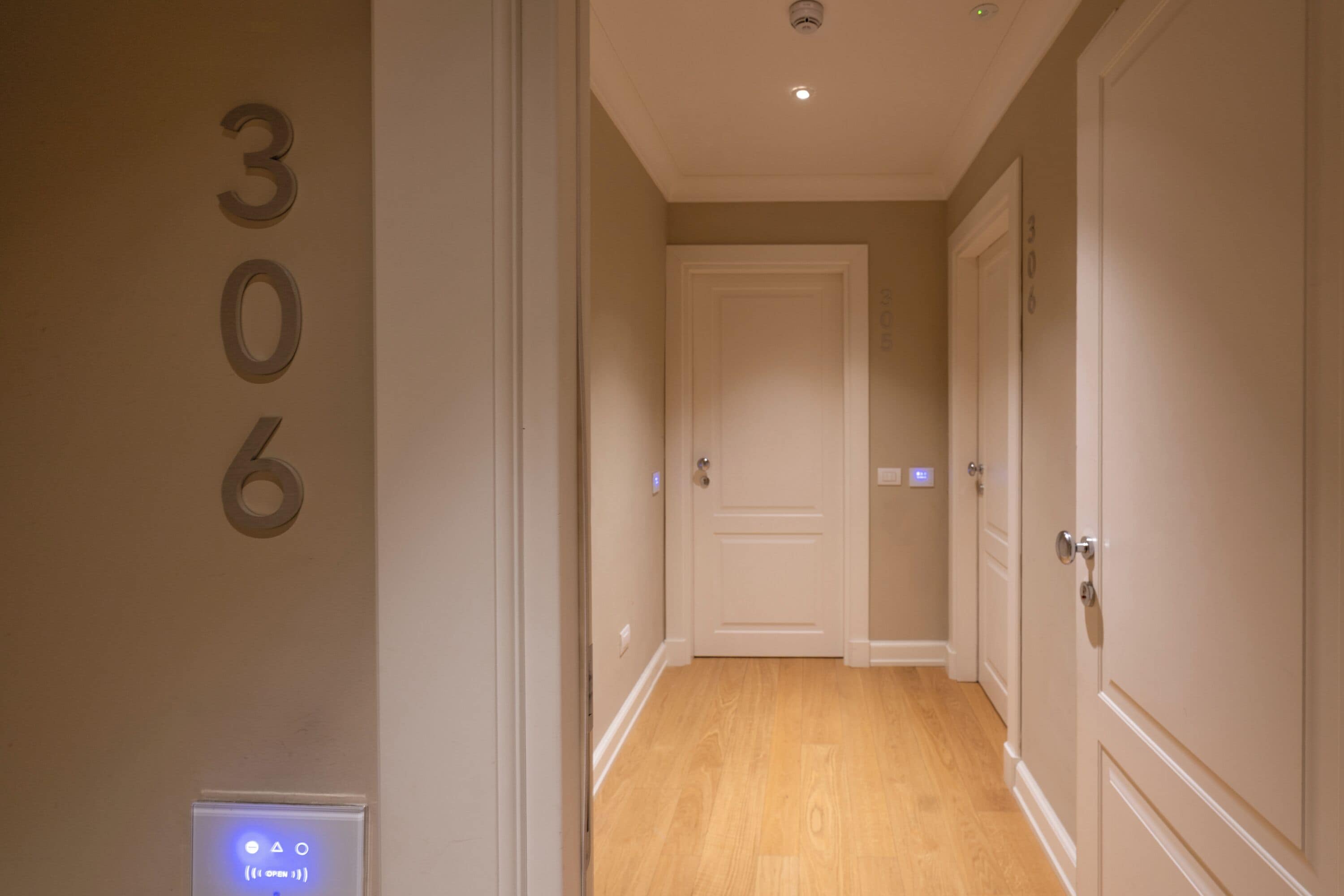 Un couloir avec une porte portant le numéro « 306 » et un interrupteur sur le mur.