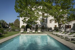A swimming pool with lounge chairs and a building in the background. - Villa Neroli (Florence)