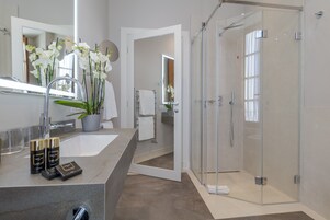 Un baño moderno con un lavamanos grande, espejo y ducha.