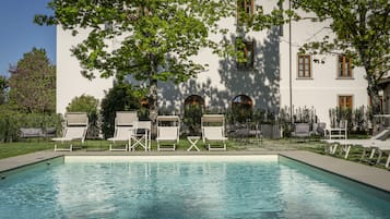 Una piscina al aire libre de temporada, sombrillas