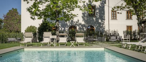 Una piscina al aire libre de temporada, sombrillas