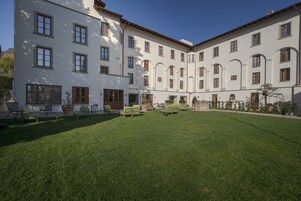 Un cortile con un edificio bianco, prato verde e posti a sedere all'aperto.