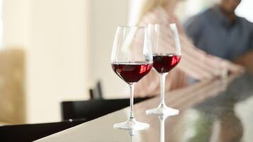 Two wine glasses on a reflective surface, likely a bar or counter, with a blurred background suggesting a social setting.
