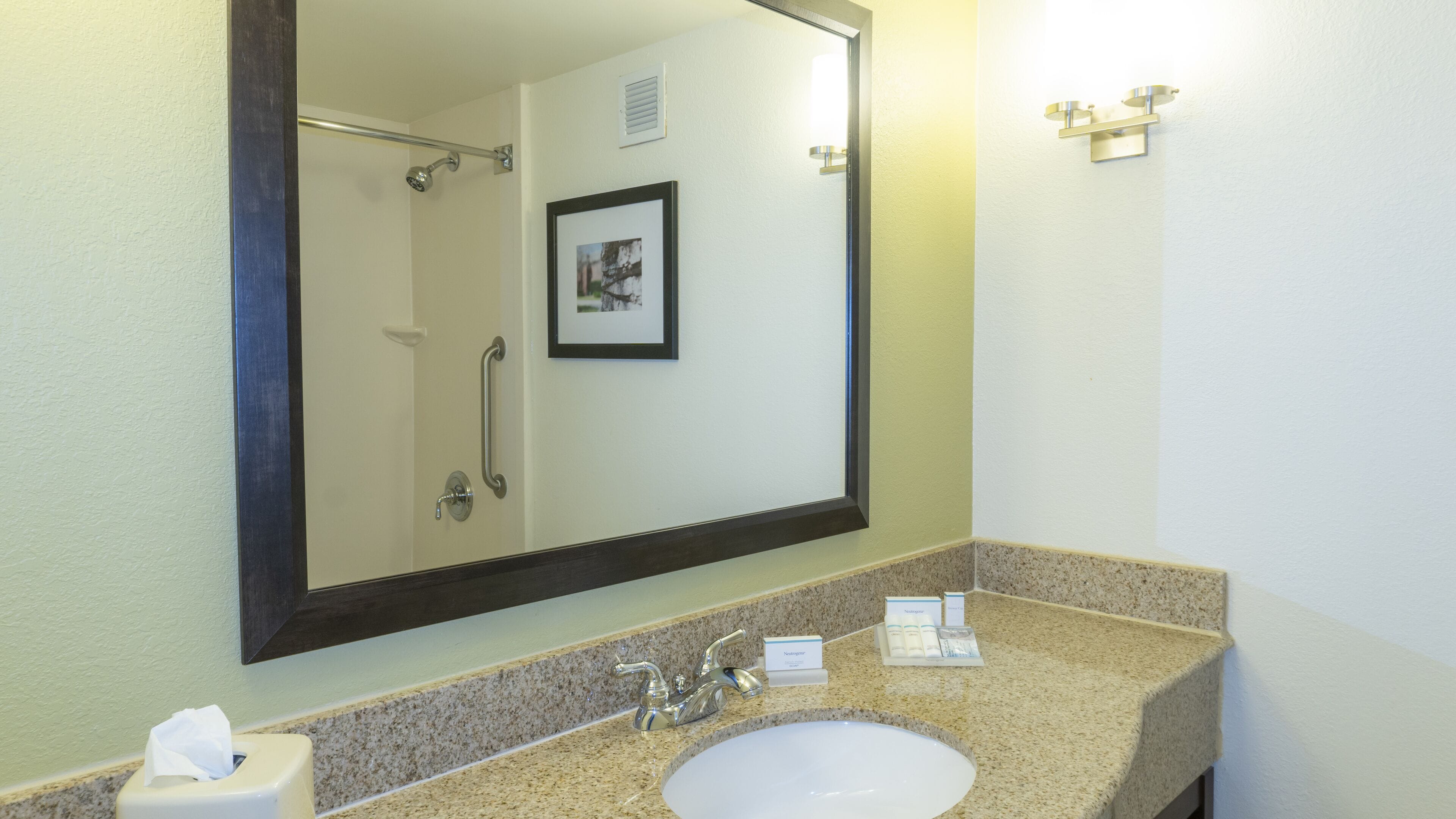 A bathroom with a sink, mirror, and shower.