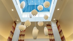Un hall d’entrée agrémenté de lanternes en papier suspendues, d’une verrière et offrant une vue sur le ciel.