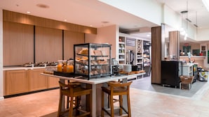 Un espace cuisine moderne avec un bar pour prendre le petit-déjeuner, des meubles en bois et une vitrine où sont exposées des pâtisseries.