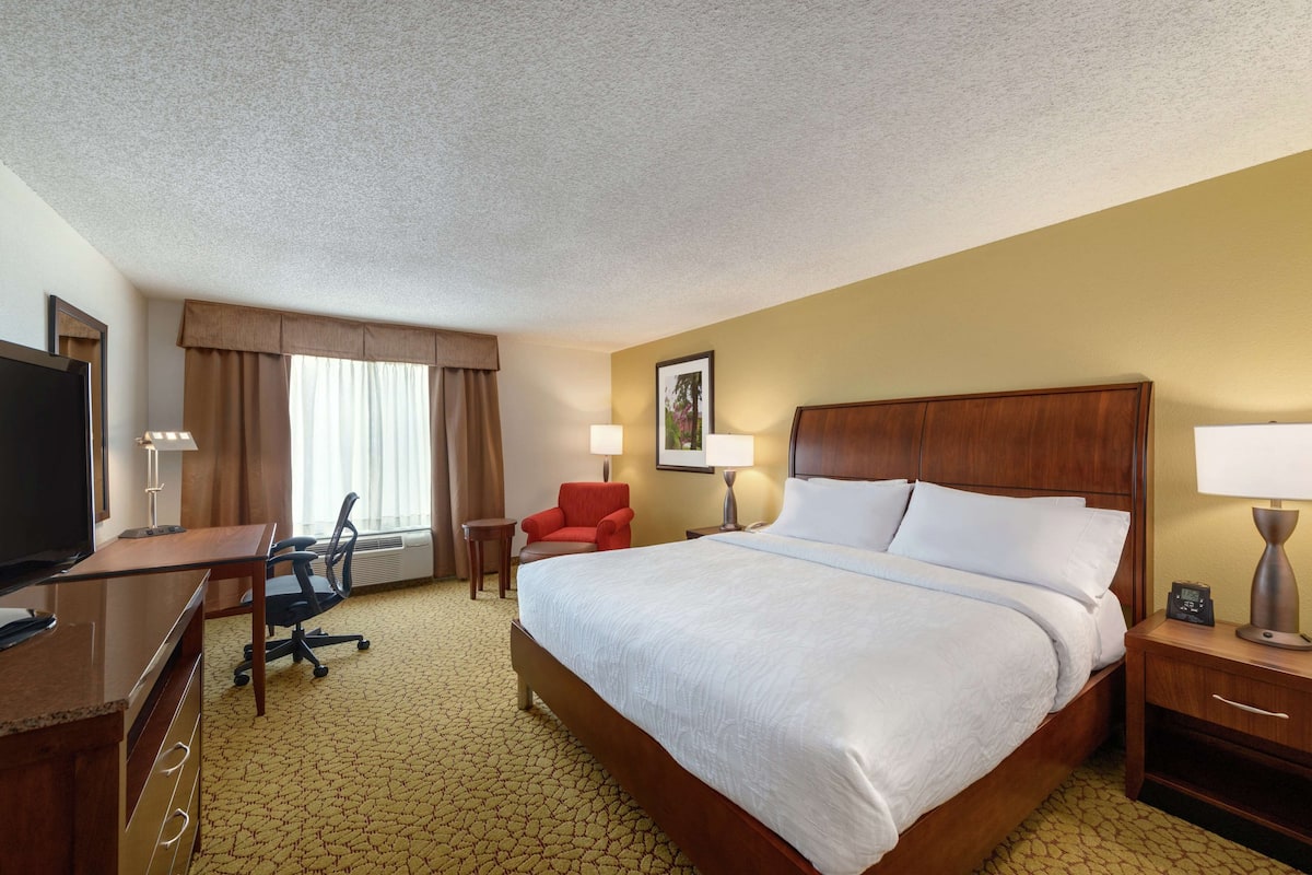 Een hotelkamer met een groot bed, een bureau met stoel, een televisie en een bijzettafeltje.
