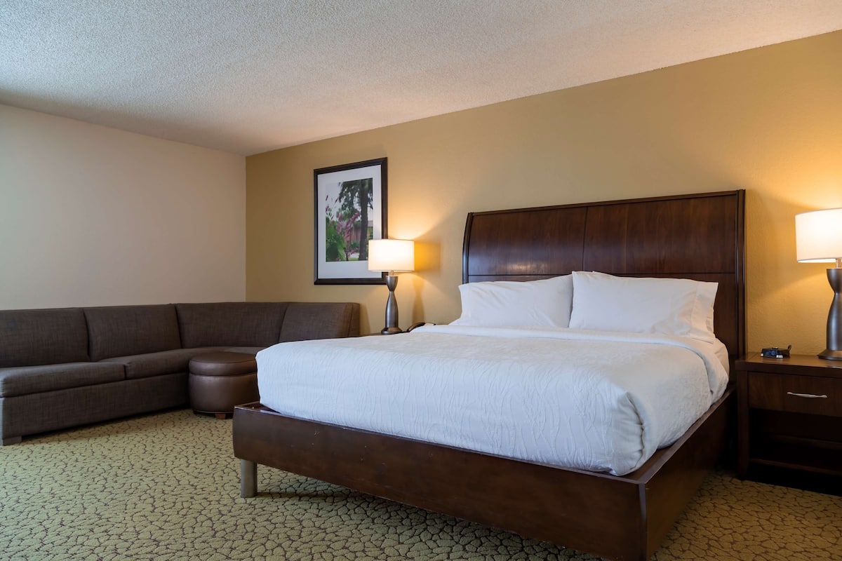 Een hotelkamer met een groot bed, een bank, een bijzettafeltje en een lamp.